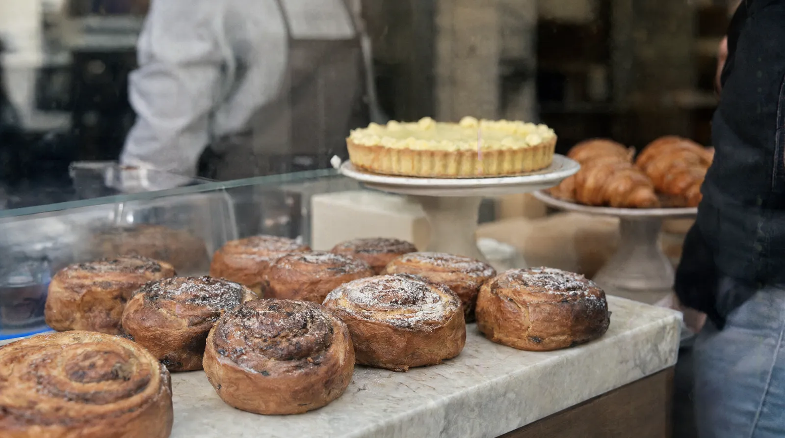 Kuchentheke mit Zimtschnecken, Zitronentarte und Croissants